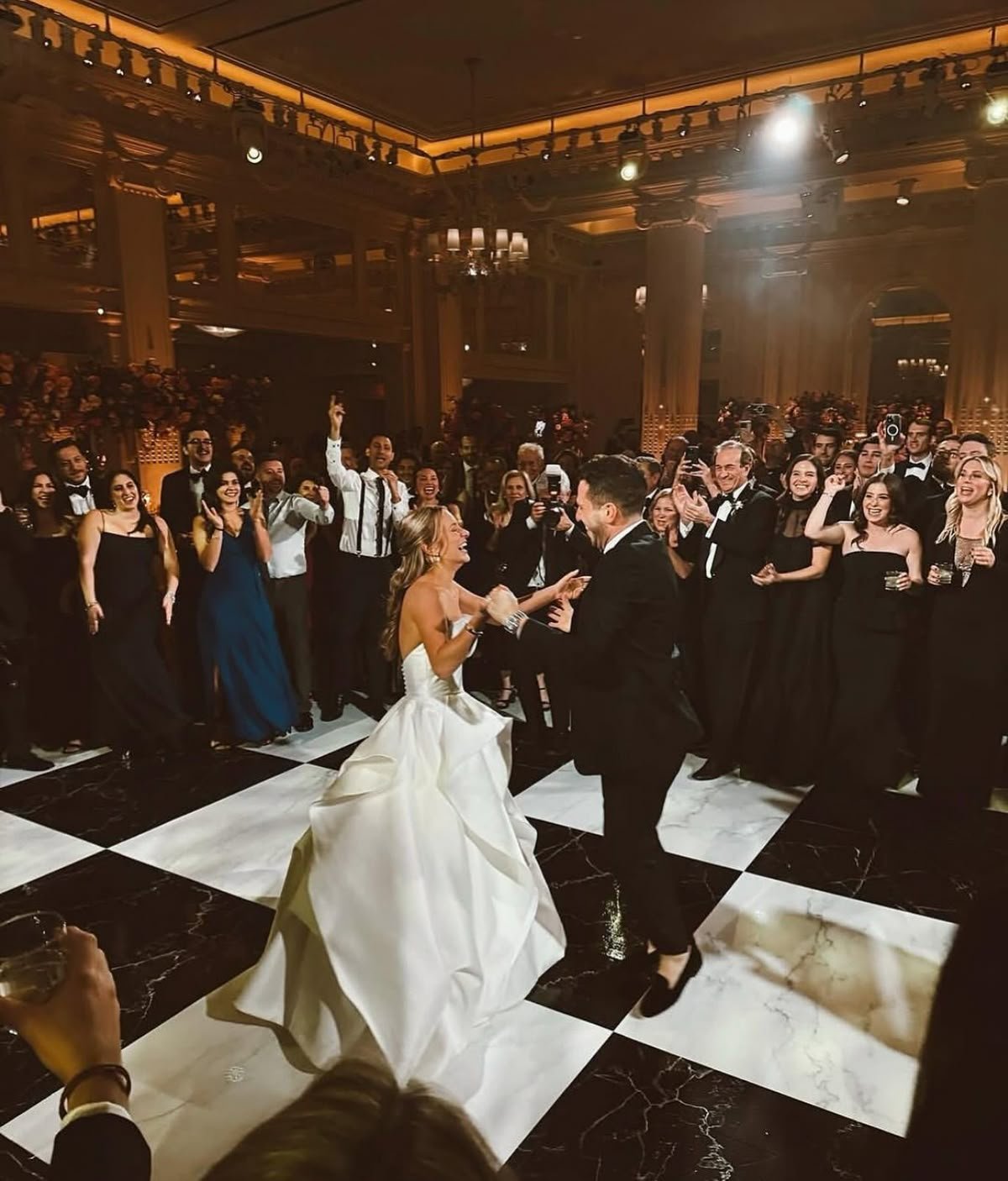 Newlyweds sharing their first dance on a checkered dance floor at an elegant Portland ballroom reception